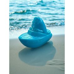 a blue toy boat sitting on top of a sandy beach