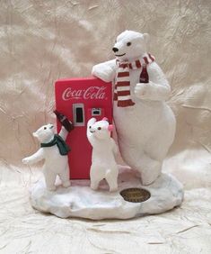 three polar bears are standing next to a coca - cola machine on a white surface