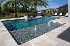 an outdoor swimming pool with water features and palm trees in the foreground, surrounded by white lounge chairs