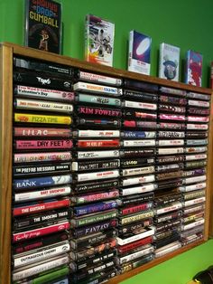 a wooden shelf filled with lots of dvd's on top of a green wall