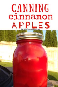 a mason jar filled with red liquid sitting on top of a table next to a grill