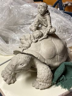 a statue of a child sitting on top of a turtle