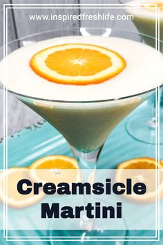 an orange and creamsice martini is garnished with sliced oranges on the rim