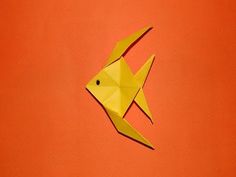 a yellow origami fish on an orange background