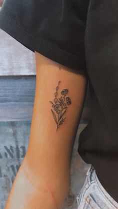 a small flower tattoo on the left inner arm and wrist, with an arrow in the center