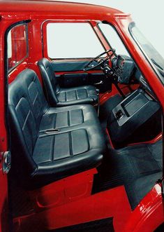 the interior of an old red truck with black seats