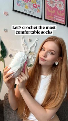 a woman with long red hair holding a pair of shoes