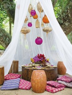 the table is set up with colorful pillows and lanterns hanging from it's ceiling