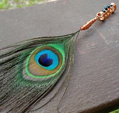 a peacock feather is attached to a wooden bench with a beaded keychain