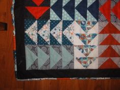 a close up of a quilt on a wooden floor with an arrow in the center