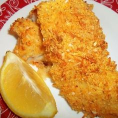 some fried food on a plate with lemon wedges and a slice of breaded chicken