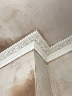 the corner of a room with moldy paint on the walls and ceiling trimming