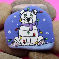 a painted rock with a dog sitting on it's side surrounded by rocks and stones