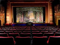 an empty theater with red seats and a painting on the wall