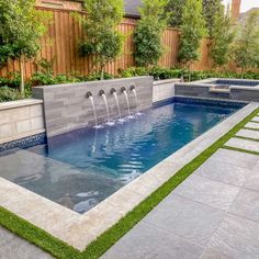 an outdoor swimming pool with artificial grass and water features in the center, surrounded by landscaping