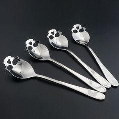 four spoons with paw prints on them sitting next to each other in front of a black background