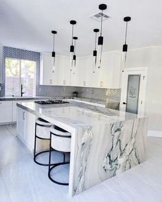 a kitchen with marble counter tops and stools next to an island in the middle