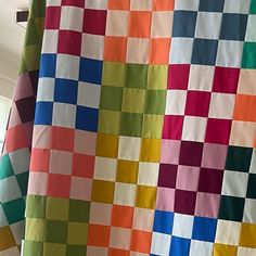 a multicolored quilt is hanging on the wall