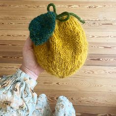 a person holding up a knitted lemon ornament