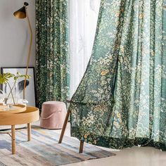 a living room with green curtains and floral print on the drapes, in front of a window