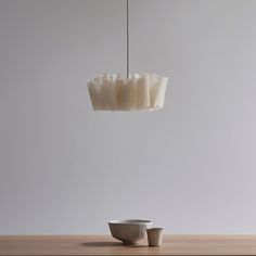 a white bowl sitting on top of a wooden table next to a hanging light fixture