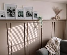 a living room with pictures on the wall and a couch in front of some windows