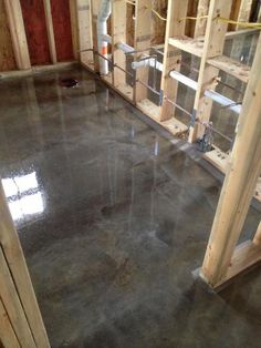 an unfinished room with concrete flooring and wooden framing on the walls, along with other construction materials