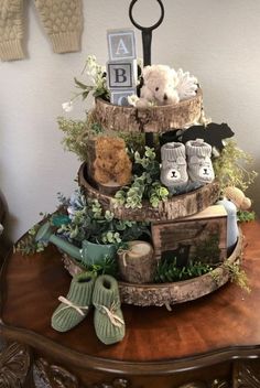 a three tiered cake decorated with baby's shoes, teddy bears and greenery