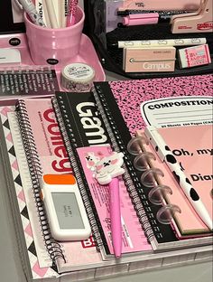 a pink desk with pens, notebooks and other office supplies