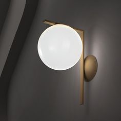 a wall mounted light on the side of a gray wall with a white ball hanging from it