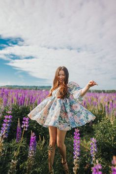 a girl in a flowery dress is walking through a field