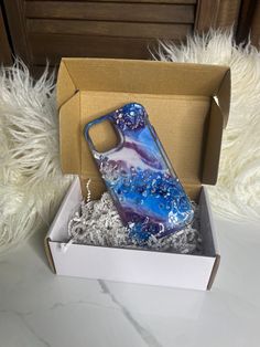 a blue and white phone case sitting in a box on top of some silver foil