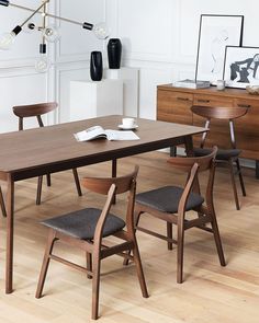 a dining room table with chairs and a book on top of it in front of a dresser