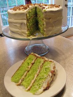 a green cake sitting on top of a table next to a slice cut out of it