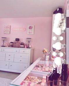 a room with pink walls and lots of makeup on the dressers in front of it