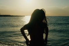 a woman standing in the water at sunset