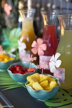 there are many different types of drinks in bowls on the table with strawberries and pineapples