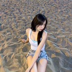 a young woman sitting on top of a sandy beach