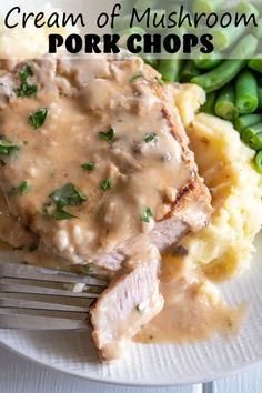 a white plate topped with meat covered in gravy next to green beans and mashed potatoes