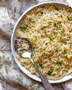 a white bowl filled with rice and garnished with parsley next to a spoon