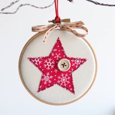 a red and white star ornament hanging from a string with a button on it