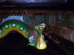 a green and white statue of a dinosaur in a room with brick walls, tiles on the floor