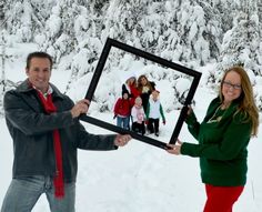 a man and woman holding up a picture frame in the snow