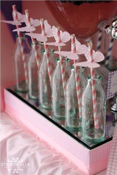 several empty glass bottles with pink and white striped straws in them on a shelf