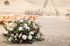 a bouquet of flowers sits on the ground in front of an empty bench at a wedding