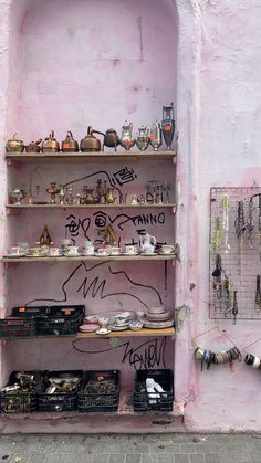 a pink wall with many shelves filled with items