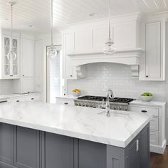 a large kitchen with white cabinets and marble counter tops, along with stainless steel appliances