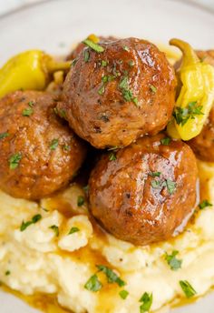 meatballs and mashed potatoes on a white plate with garnished green herbs