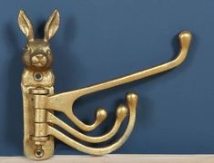 a golden metal hook with a rabbit on it's side and a wooden table in the background