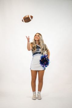 a cheerleader is throwing a football into the air while posing for a photo with her pom poms